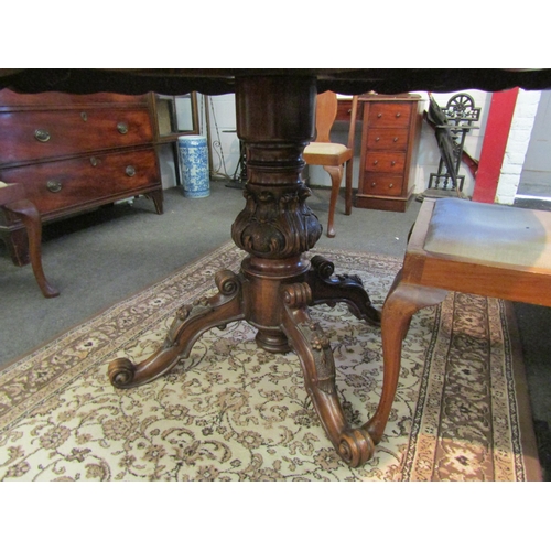 1021 - A Victorian mahogany circular breakfast table with scalloped apron and ornate column to a carved qua... 