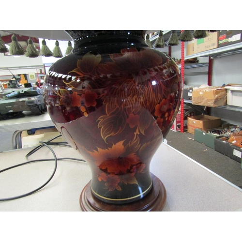 1072 - A red bulbous form table lamp with ornate tasselled shade