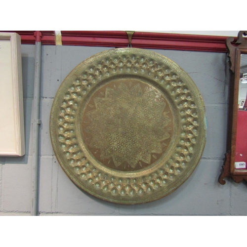 1043 - An Islamic brass charger. Tooled and hammered decoration. 60.5cm diameter