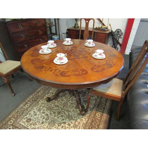 1111 - A Victorian mahogany circular breakfast table with scalloped apron and ornate column to a carved qua... 