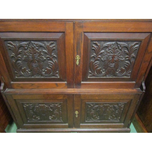 4128 - An oak hall cupboard with carved Green Man panels.  Shelved interior to cupboard doors.  121cm wide ... 