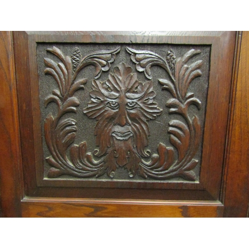 4128 - An oak hall cupboard with carved Green Man panels.  Shelved interior to cupboard doors.  121cm wide ... 