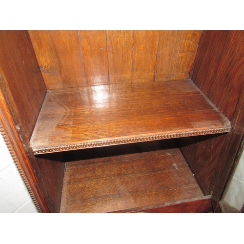 1008 - An oak cupboard with glazed door, shelved interior over open undershelf, ornately carved sides and r... 