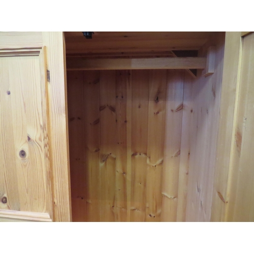 1058 - A natural pine compactum wardrobe, the two doors over two drawers, 200cm high x 104cm wide x 55cm de... 