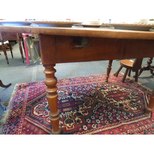 1121 - A late 19th Century fruitwood kitchen table with drop sides on turned legs