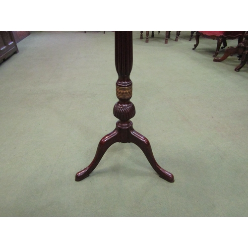 4151 - A mahogany torchere the dished circular top on turned and carved fluted column, decorative brass ban... 