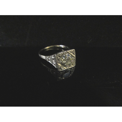 6237 - An Art Deco style ring, with a 1ct approx diamond to centre in squared setting, scrolled shoulders s... 