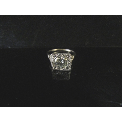 6237 - An Art Deco style ring, with a 1ct approx diamond to centre in squared setting, scrolled shoulders s... 