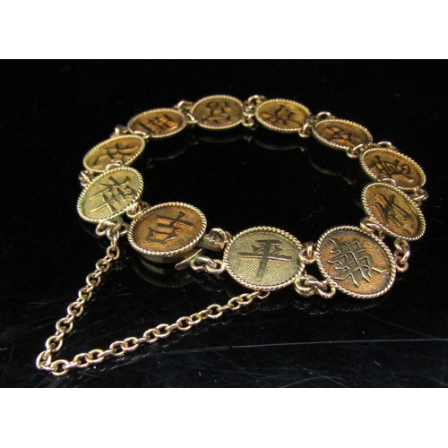 6064 - A gold Oriental character mark panel bracelet marked 18, 15g