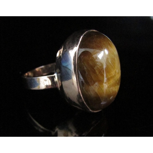 6141 - A gold ring set with a large cabochon tigers eye. Size O, 6.8g