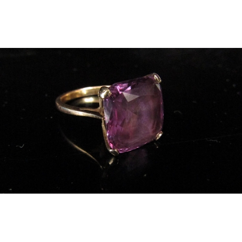 6195 - An unmarked gold ring set with a large square purple stone, possibly a synthetic violet sapphire. Si... 