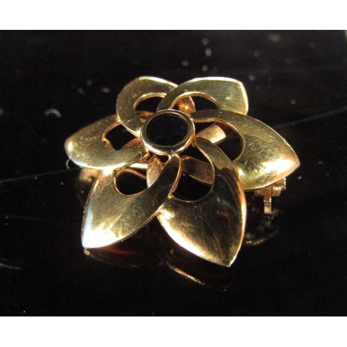 6199 - A gold floral form brooch centrally set with a sapphire, stamped 750, 3.4g