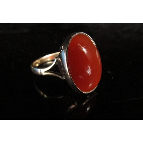 6200 - An unmarked gold ring with a cornelian oval stone in rubover setting. Size O, 4.8g