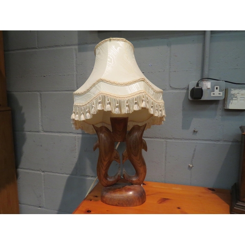 1085 - A carved hardwood figural table lamp in the form of dolphins with pleated shade