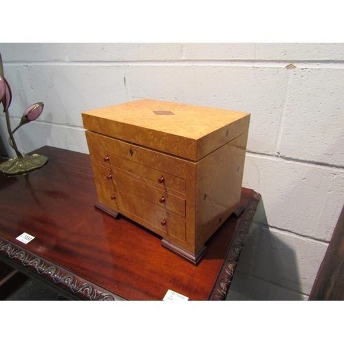 1033 - A burr wood jewellery box, the lift lid opening to reveal sectional space, over three graduated fron... 