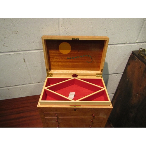 1033 - A burr wood jewellery box, the lift lid opening to reveal sectional space, over three graduated fron... 