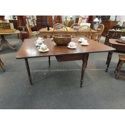 1174 - An early 20th Century oak drop leaf dining table with turned supports on castors