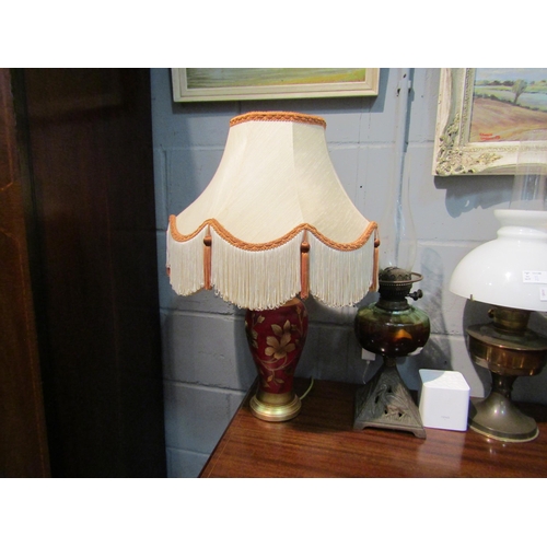 1057 - A pair of red and gilt floral design table lamps with tasselled shades