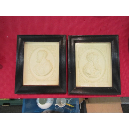 1556 - A pair of white plaster relief moulded plaques in black reeded frames