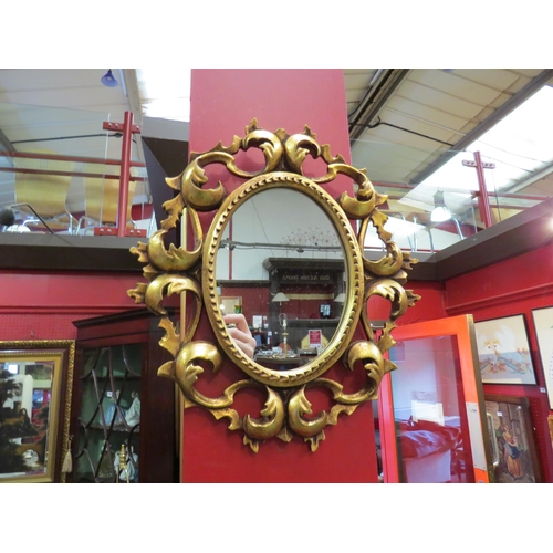 4072 - A George II revival oval mirror with ornate scroll leaf gilt frame, 29cm x 26cm total  (R)    £35