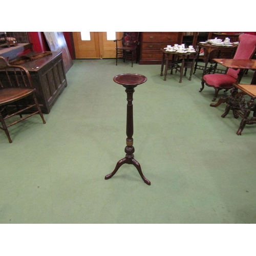 4149 - A mahogany torchere the dished circular top on turned and carved fluted column, decorative brass ban... 