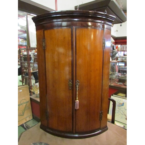 4240 - A circa 1790 Lancashire cross banded mahogany and oak bow front corner cupboard, the two doors with ... 