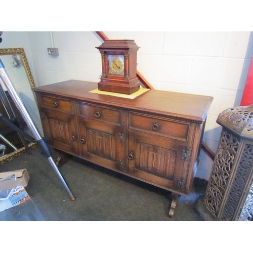 1004 - An Old Charm style sideboard with linen fold decoration, three drawers over three doors on stretcher... 