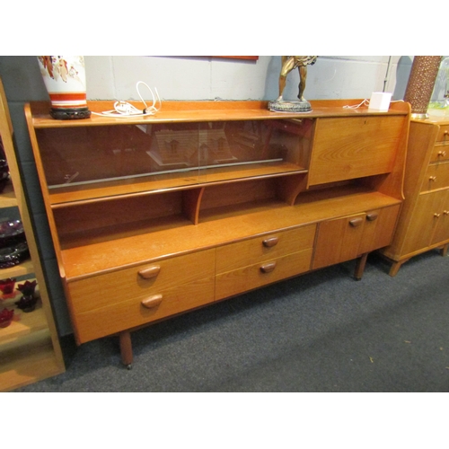 1036 - A retro 1960’s teak sideboard with glazed display section, drop-flap, four drawers and two cupboard ... 