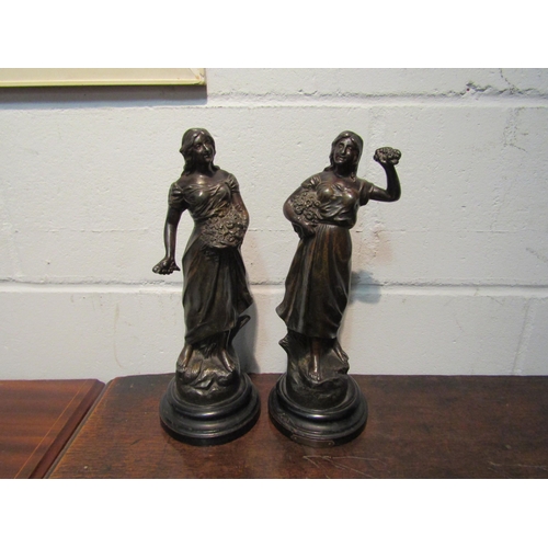 1053 - A pair of spelter bronze effect figures of ladies holding baskets of flowers. 32cm high  (R) £20