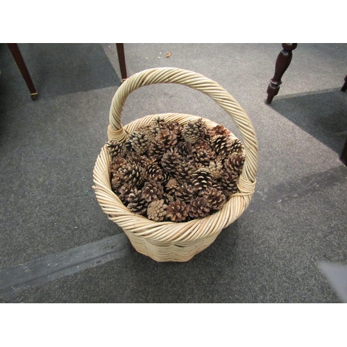 1104 - A large handled wicker basket containing a quantity of pine cones