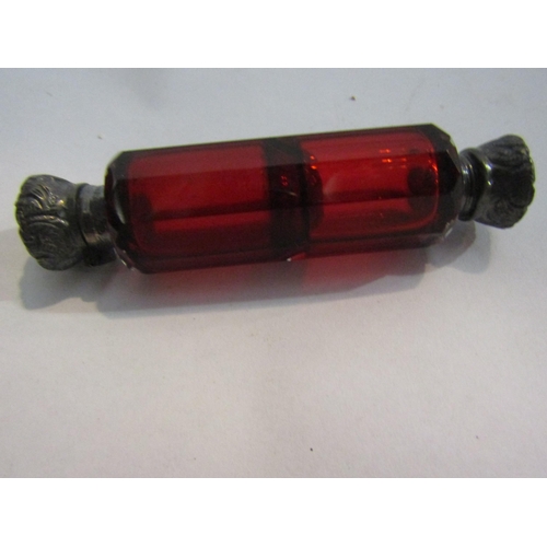 4262 - A faceted red glass double ended scent bottle with silver repousse hinged lids