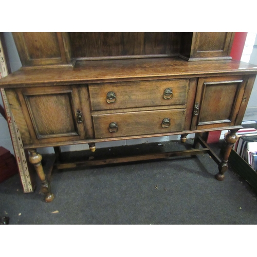 1001 - An early 20th Century oak dresser, the arched plate rack top over two drawer and twin cupboard base,... 