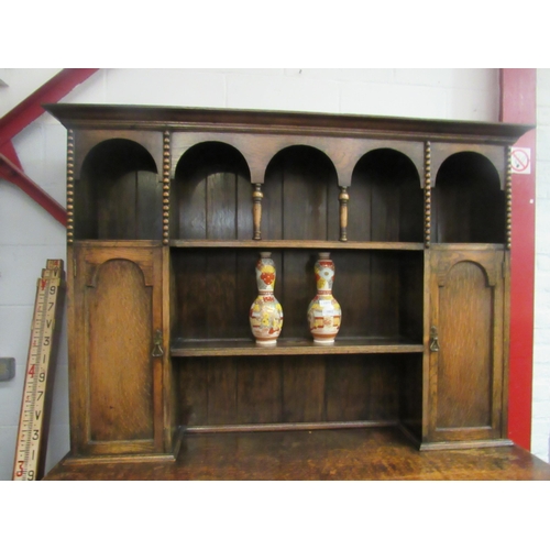 1001 - An early 20th Century oak dresser, the arched plate rack top over two drawer and twin cupboard base,... 