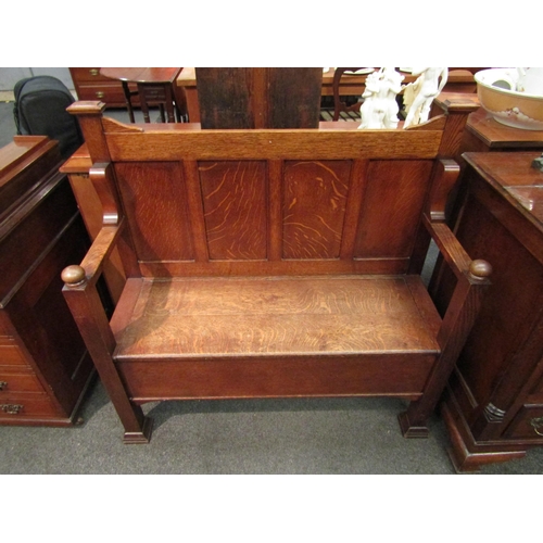 1126 - An Arts & Crafts honey oak hall settle / bench with four panel back, seat storage, square legs to st... 