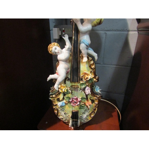 1143 - A Continental ceramic table/floor lamp in the form of violin and putti embellished with flowers and ... 