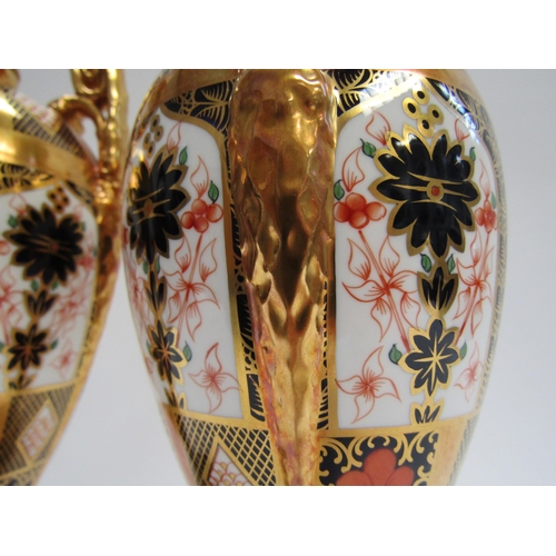 5116 - A pair of Royal Crown Derby Imari pattern urns, ovoid form with fixed knop cover and two high loop h... 