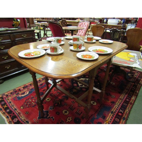 4061 - An oak drop-leaf table on turned supports and stretcher base