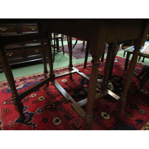 4061 - An oak drop-leaf table on turned supports and stretcher base