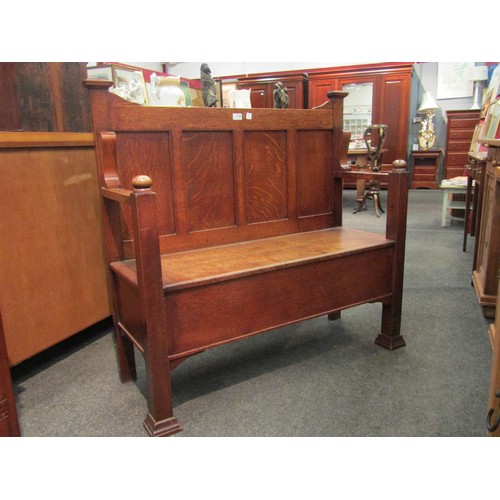 1126 - An Arts & Crafts honey oak hall settle / bench with four panel back, seat storage, square legs to st... 