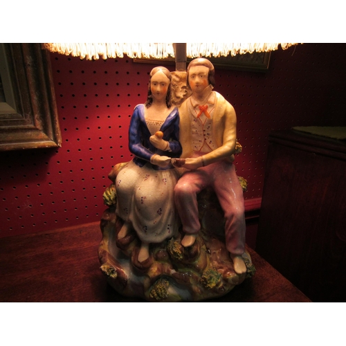 4026 - A Staffordshire table lamp in the form of a courting couple together with a silk pleated and tassell... 