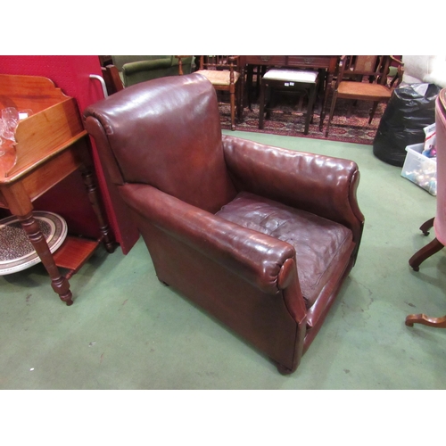 4098 - Circa 1920 a leather gentlemans club armchair, the scroll arms over bun feet and ceramic castors