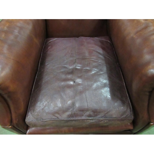 4098 - Circa 1920 a leather gentlemans club armchair, the scroll arms over bun feet and ceramic castors