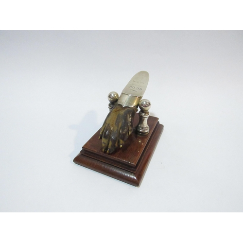 4102 - A silver mounted paw in the form of a letter clip on a wooden plinth