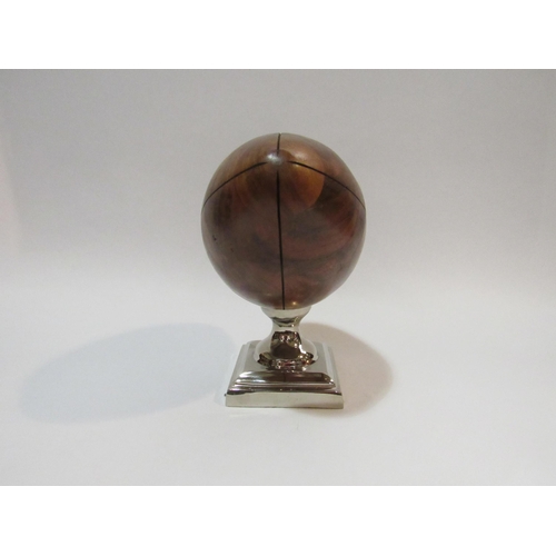 4277 - A walnut rugby ball desk top trophy on a stepped chrome square base, 21cm high