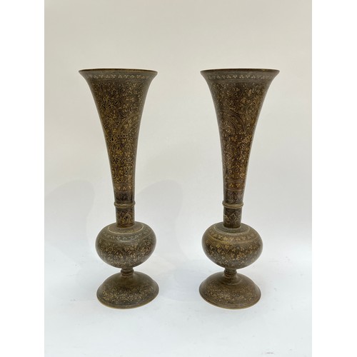 4142 - A pair of Middle-Eastern brass trumpet-form vases with all-over foliate pattern, 36cm tall