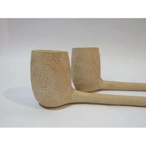 4335 - A pair of large clay pipes with etched decoration to the bowls, 45cm long