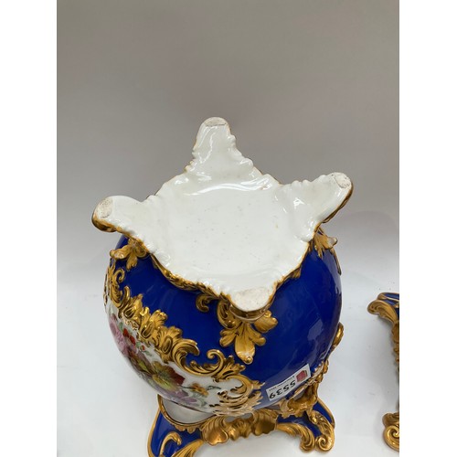 4170 - A pair of Rockingham porcelain lidded urns, blue ground with floral panels, enriched with gilt, heav... 