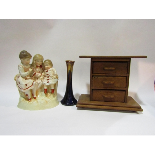 4309 - A wooden three drawer cabinet of miniature form, together with a ceramic figure group of three child... 