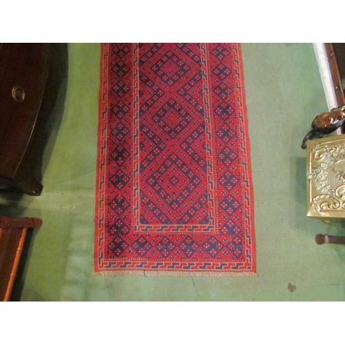 4195 - A runner rug, red ground with diamond pattern, 242cm x 64cm