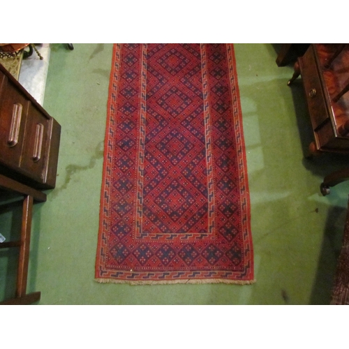 4195 - A runner rug, red ground with diamond pattern, 242cm x 64cm